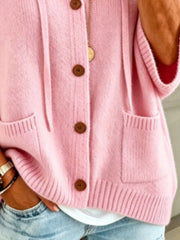 Detail view of the pink cardigan showing brown buttons, patch pockets and ribbed hem