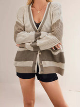 Front view of khaki and cream color block V neck cardigan with arms crossed and black shorts