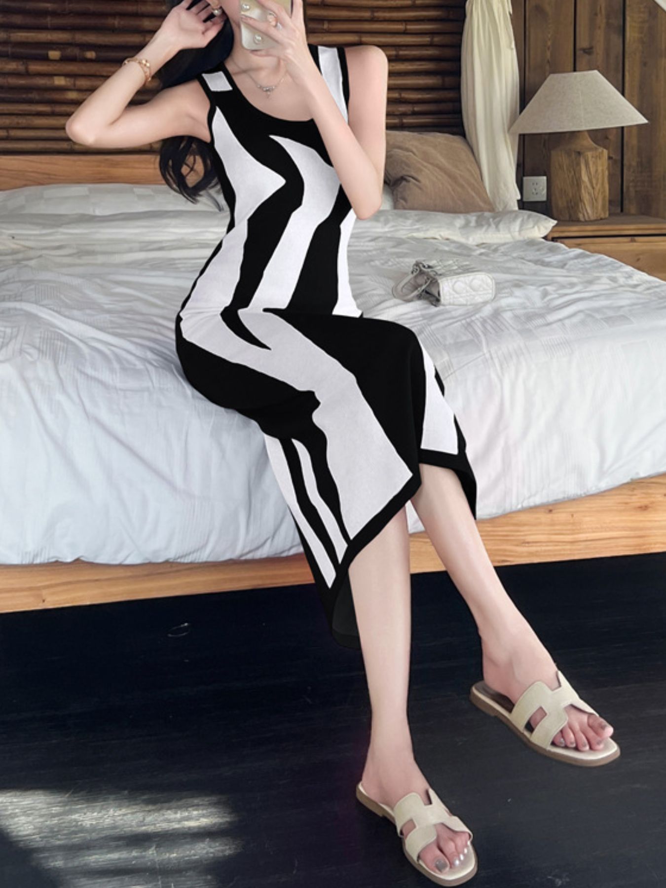 Seated mirror view of the black and white wavy contrast sleeveless bodycon midi dress indoors