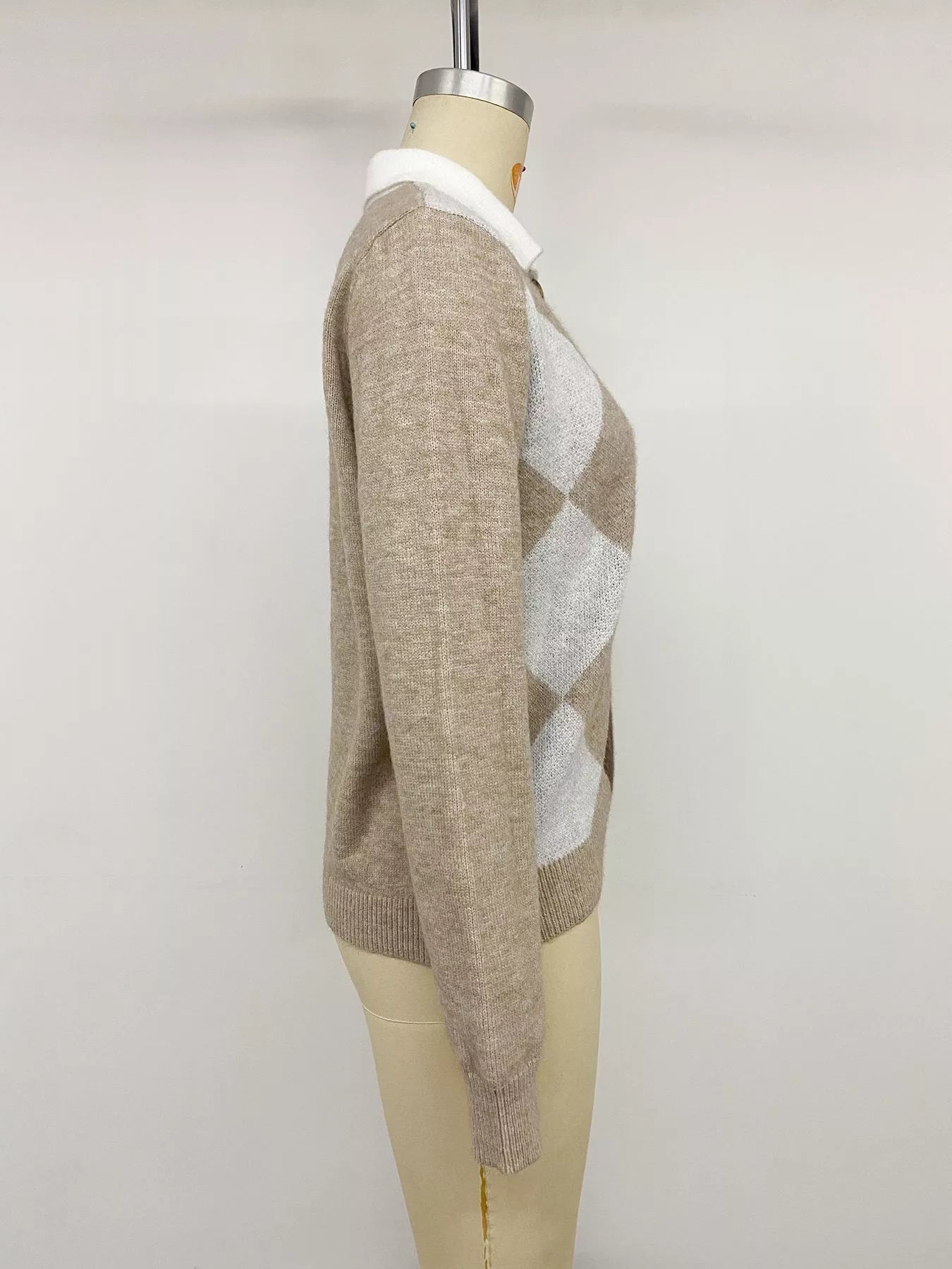 Side view of the beige, brown, and white argyle polo sweater on a mannequin