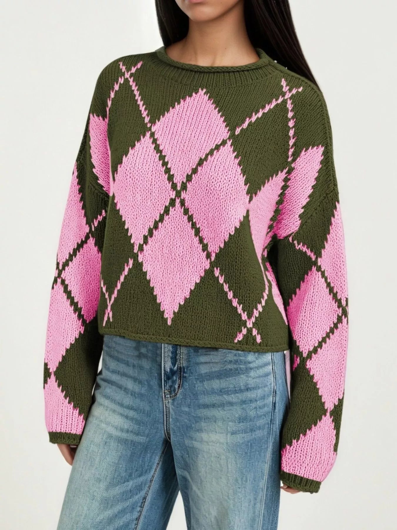 On-model front view of an olive green and pink argyle knit sweater with dropped shoulders