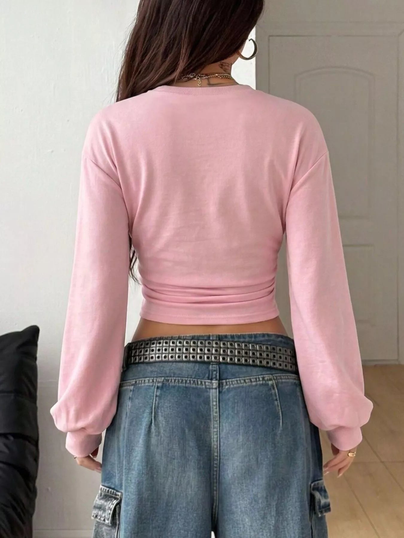 Back view of pink long sleeve cropped t shirt with wide sleeves and jeans