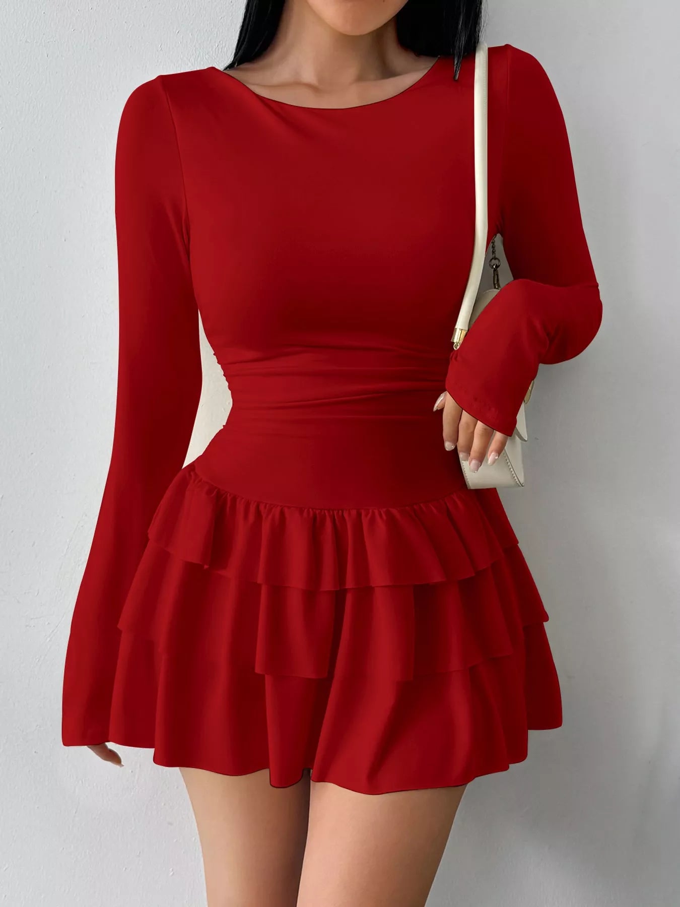 Red layered ruffle long sleeve mini dress worn front facing with a white shoulder bag