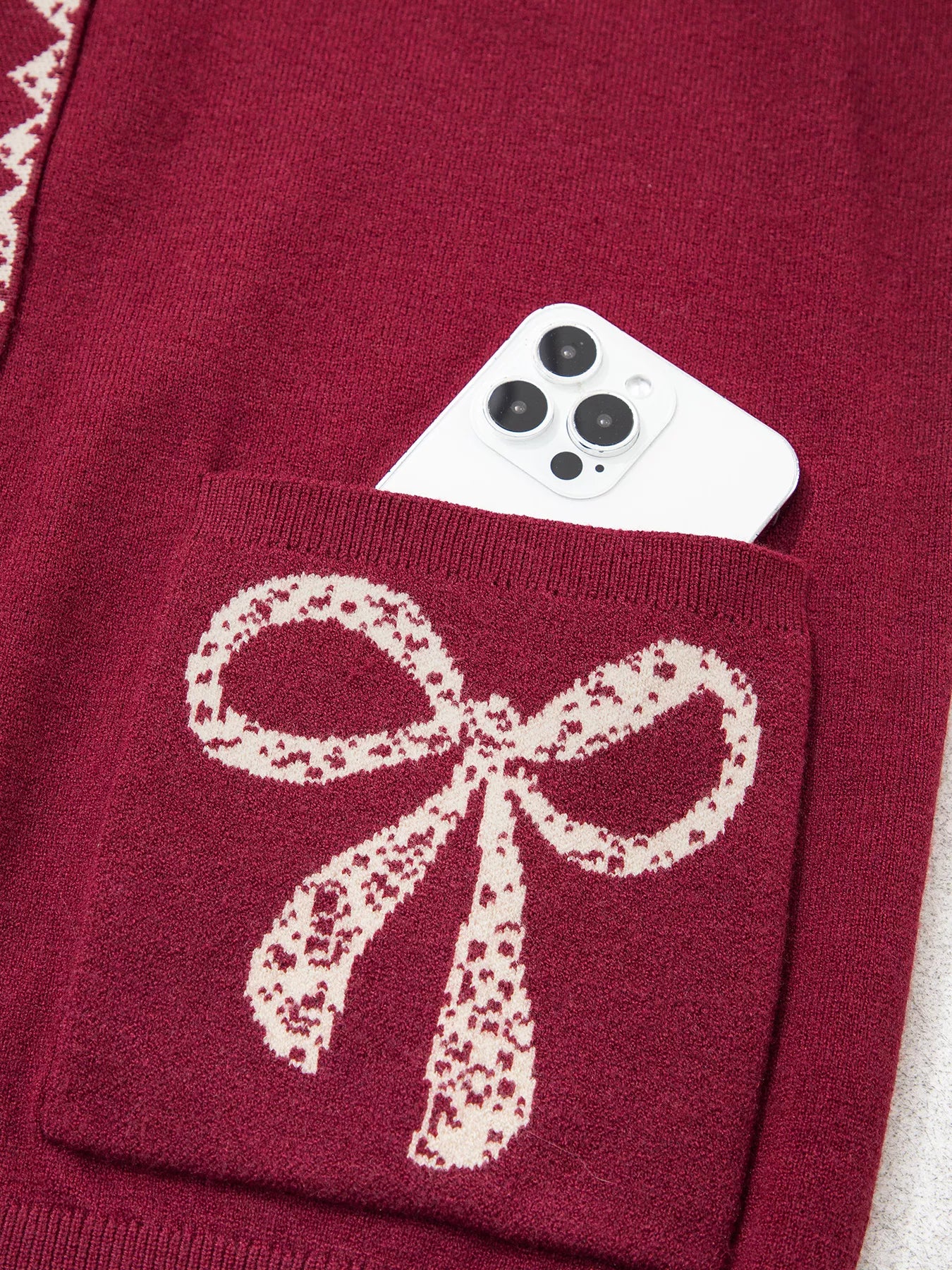 Close view of the burgundy bow pocket holding a white phone
