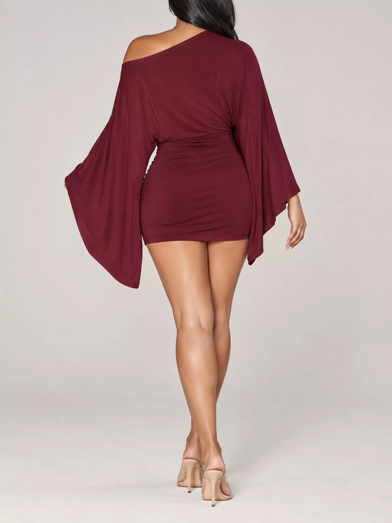 Back studio view of burgundy one shoulder draped bodycon mini dress with wide sleeves
