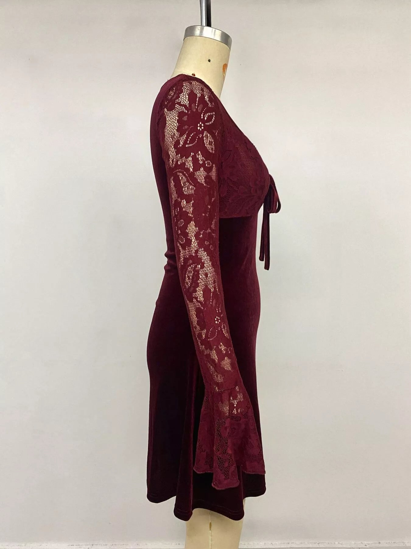 Side view of burgundy lace mini dress on mannequin showing flared lace sleeve