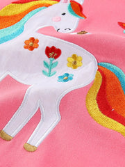 Close view of the embroidered white unicorn body with colorful flowers on pink fabric