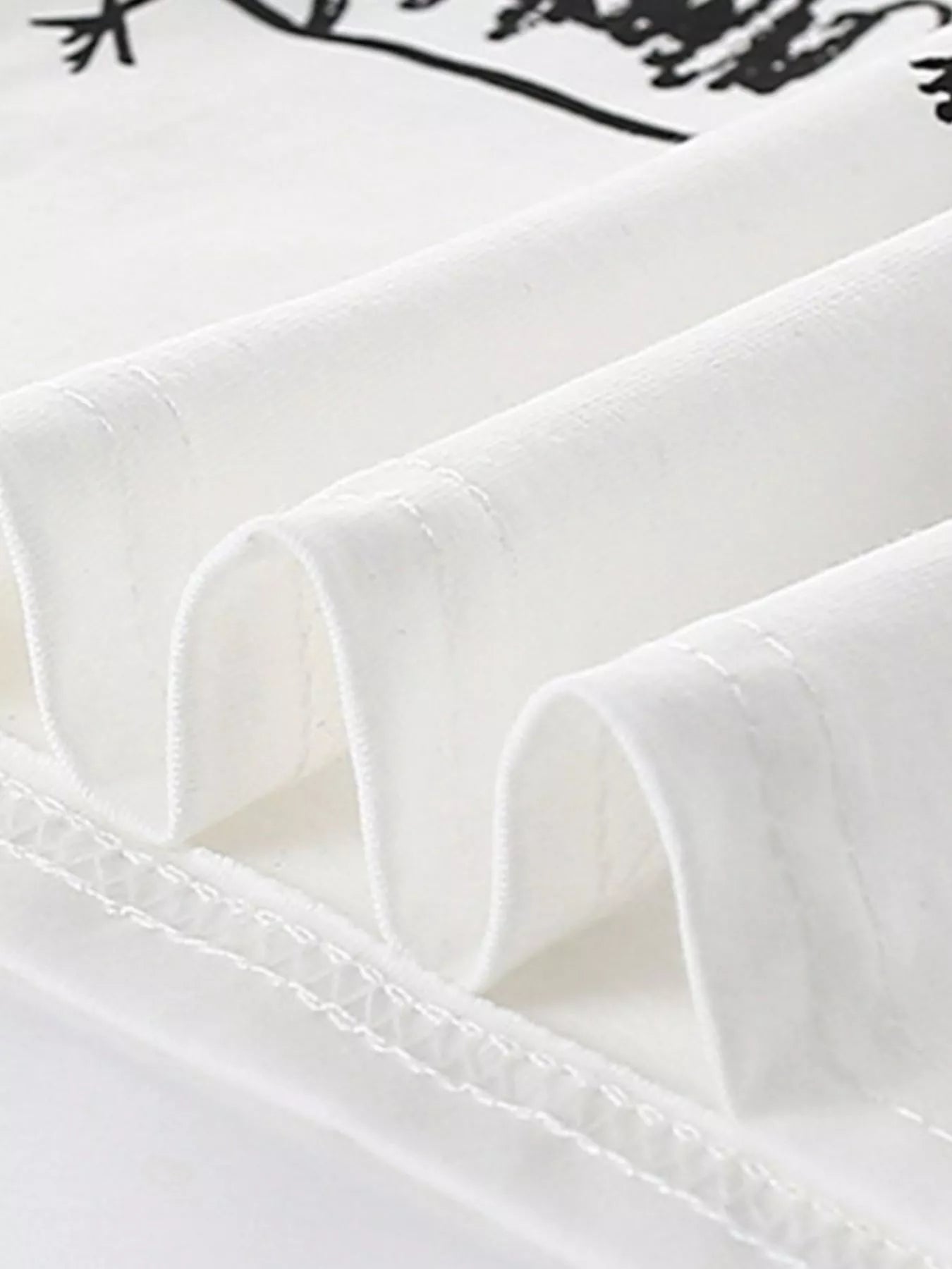 Close-up of the white shirt hem showing neat stitching and soft folded fabric