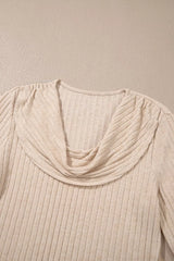 Close-up detail of a beige ribbed long-sleeve top featuring a draped cowl neckline