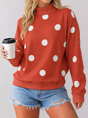 Front view of red mock neck oversized sweatshirt with white polka dots holding a cup