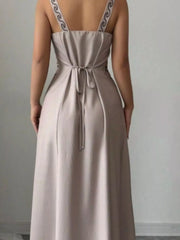 Close back view of gray maxi dress showing tied waist and patterned straps