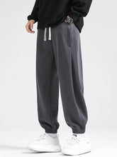 Men's dark gray loose-fit joggers with a drawstring waist and pockets.