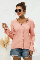 Coral pink V-neck shirt with ruffle trim, flounce sleeves, button front, and gathered cuffs on model