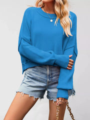 Front view of a bright blue crew neck dropped shoulder sweater with ribbed cuffs worn with denim shorts.