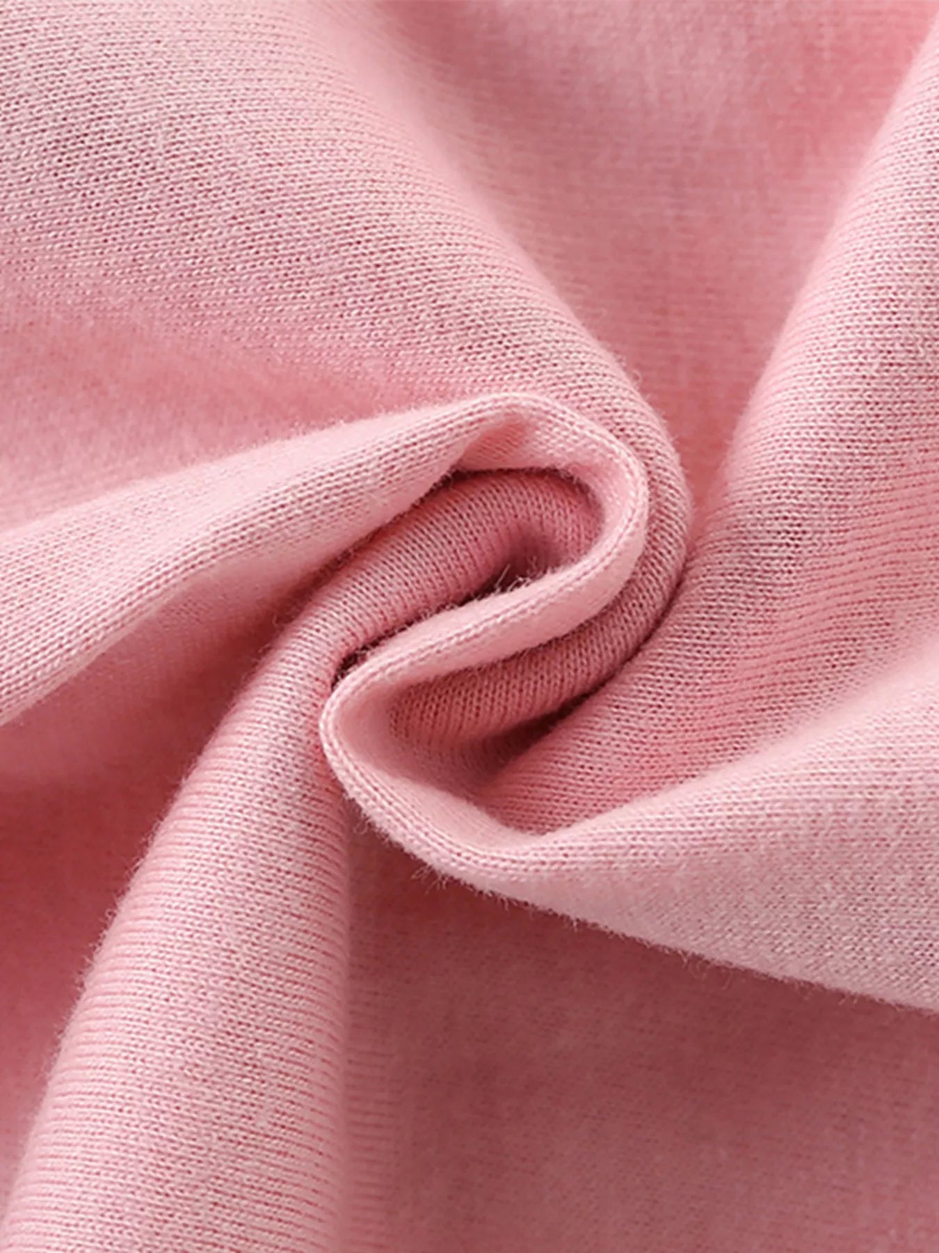 Close-up of soft folded blush pink knit fabric texture of children's short sleeve t-shirt