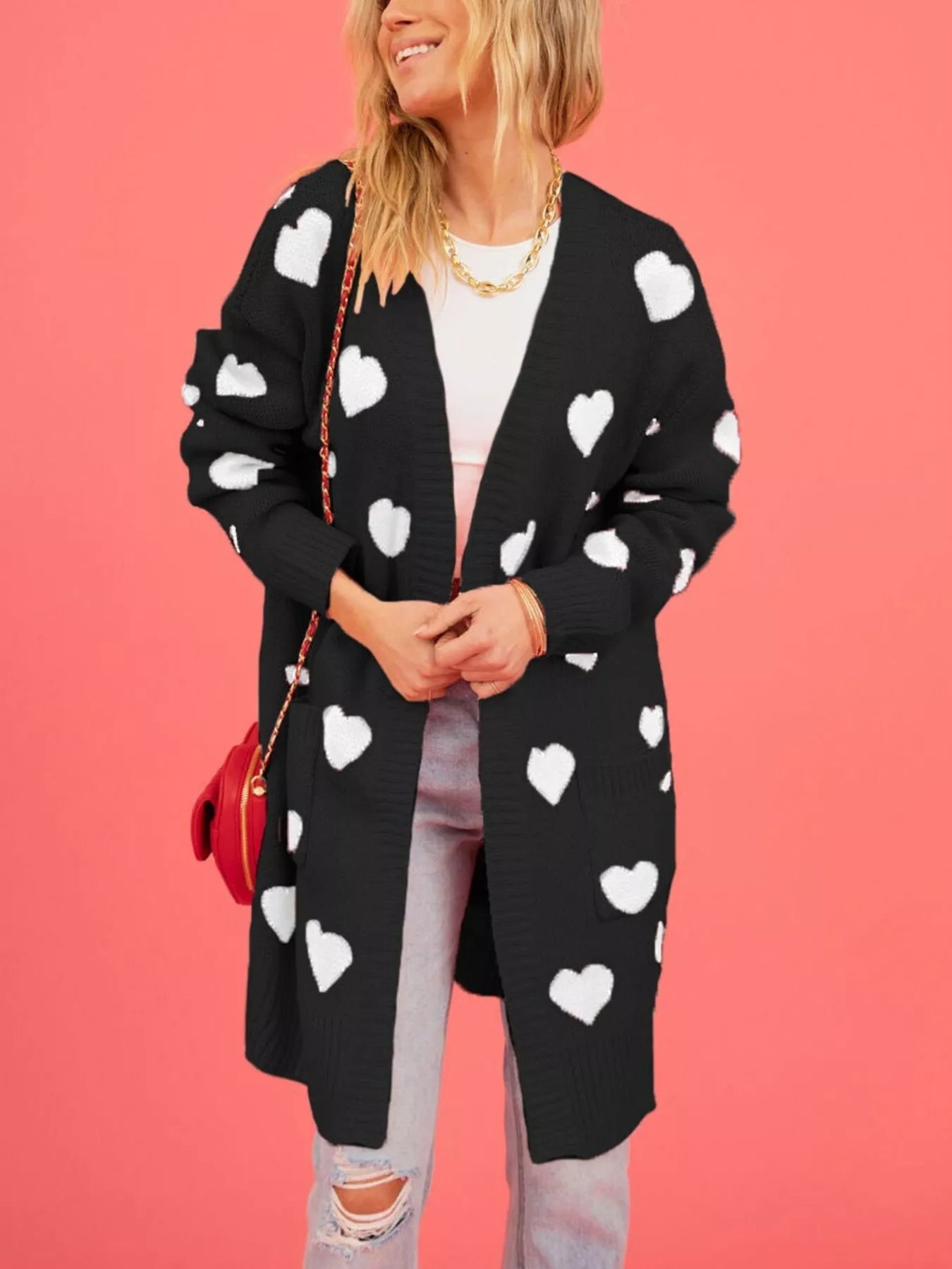 Front view of a black longline cardigan with white hearts worn open