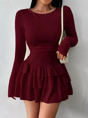 Burgundy layered ruffle long sleeve mini dress worn front facing with a white shoulder bag