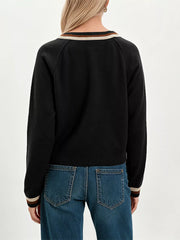 Back view on-model of black button down cardigan with cream and brown striped neckline and cuffs