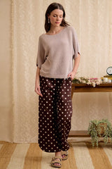 Full length front view of washed mocha dolman knit top with hand in pocket.