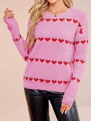 On-model front view of a pink dropped shoulder sweater with red heart stripes, arm raised