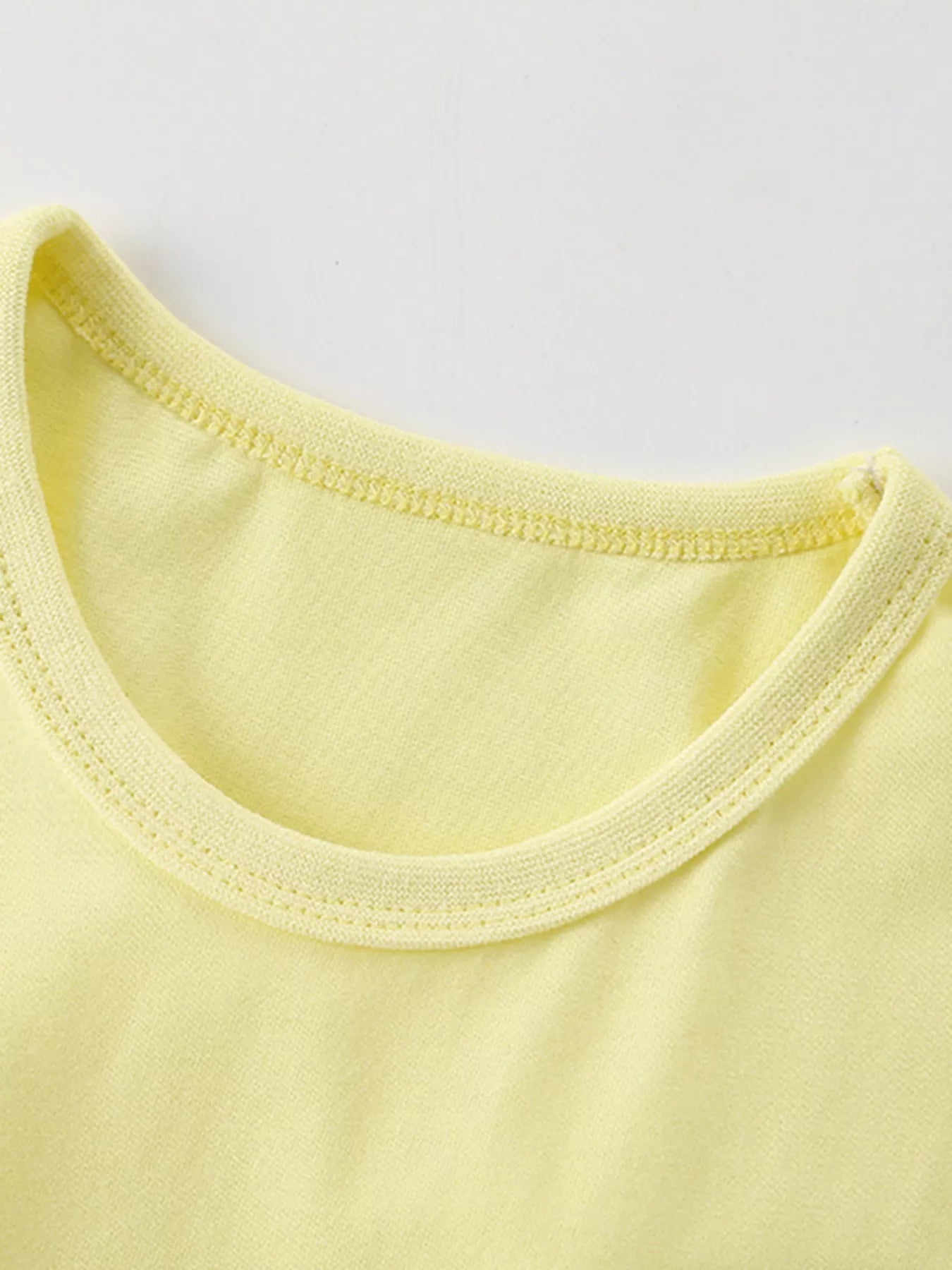 Close-up of the light yellow shirt neckline showing ribbed trim and neat stitching