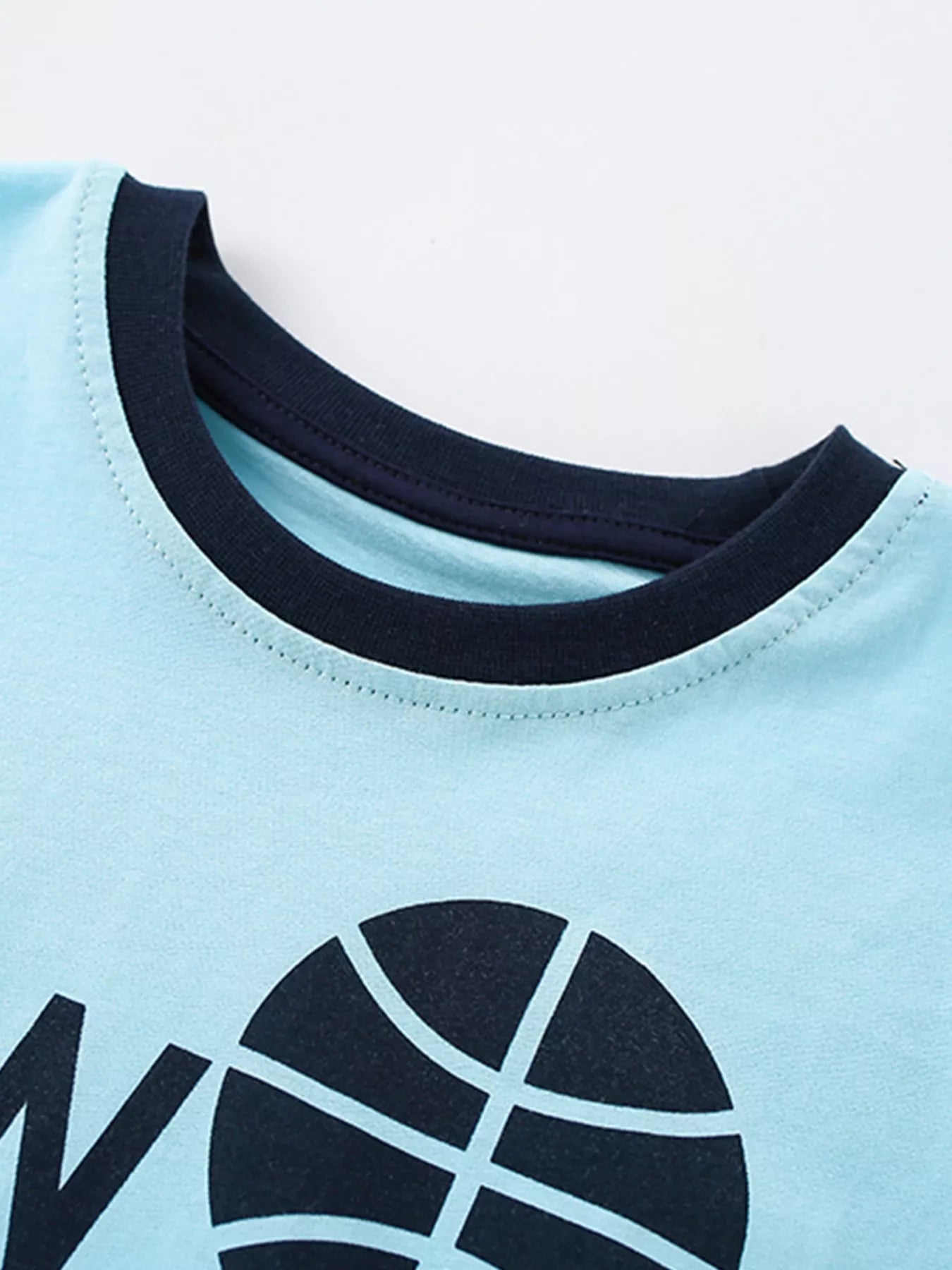 Close-up of the contrast navy round neckline with neat stitching above the basketball graphic