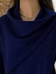 Close-up of the navy cowl neckline showing the draped asymmetric collar and fine knit texture
