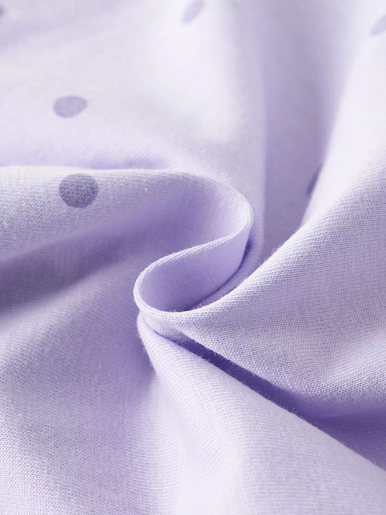 Close view of the soft lavender polka dot fabric of a children's t shirt
