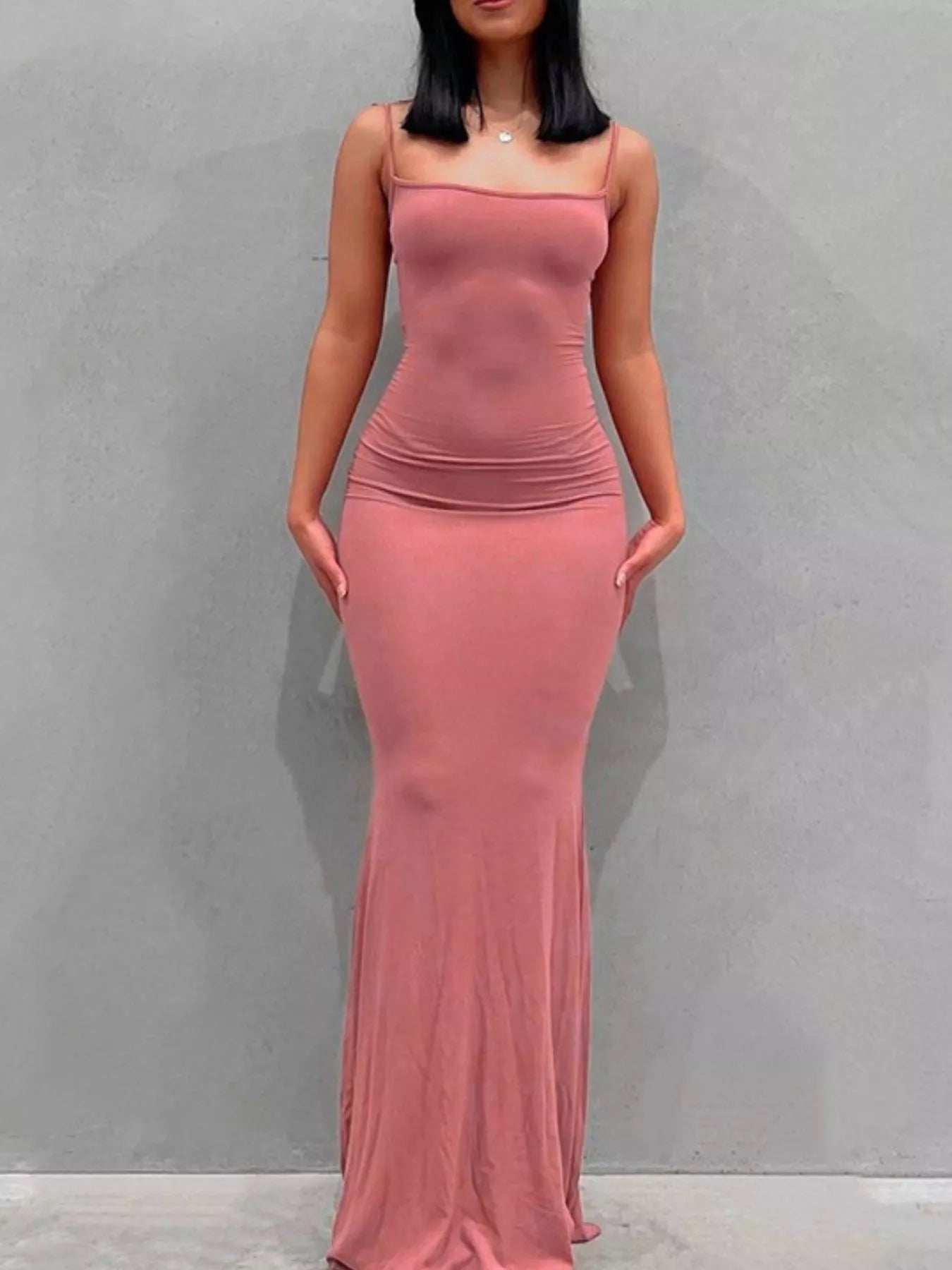 Front view of a burnt coral spaghetti strap bodycon maxi dress against a plain gray wall