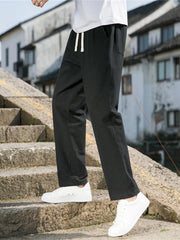Men's black loose-fit casual pants with a drawstring waist and pockets.