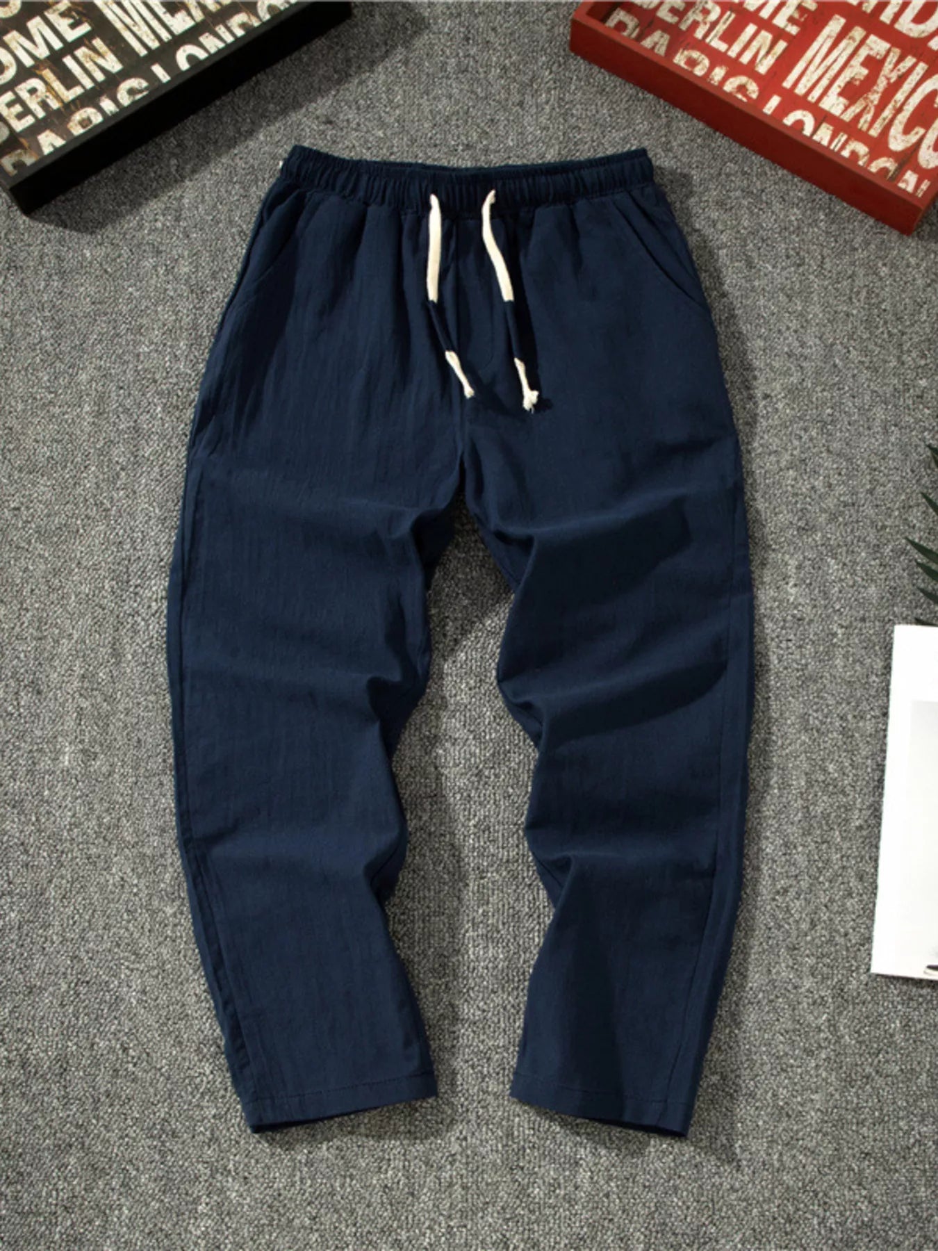 Men's navy loose-fit pants with a drawstring waist and pockets.