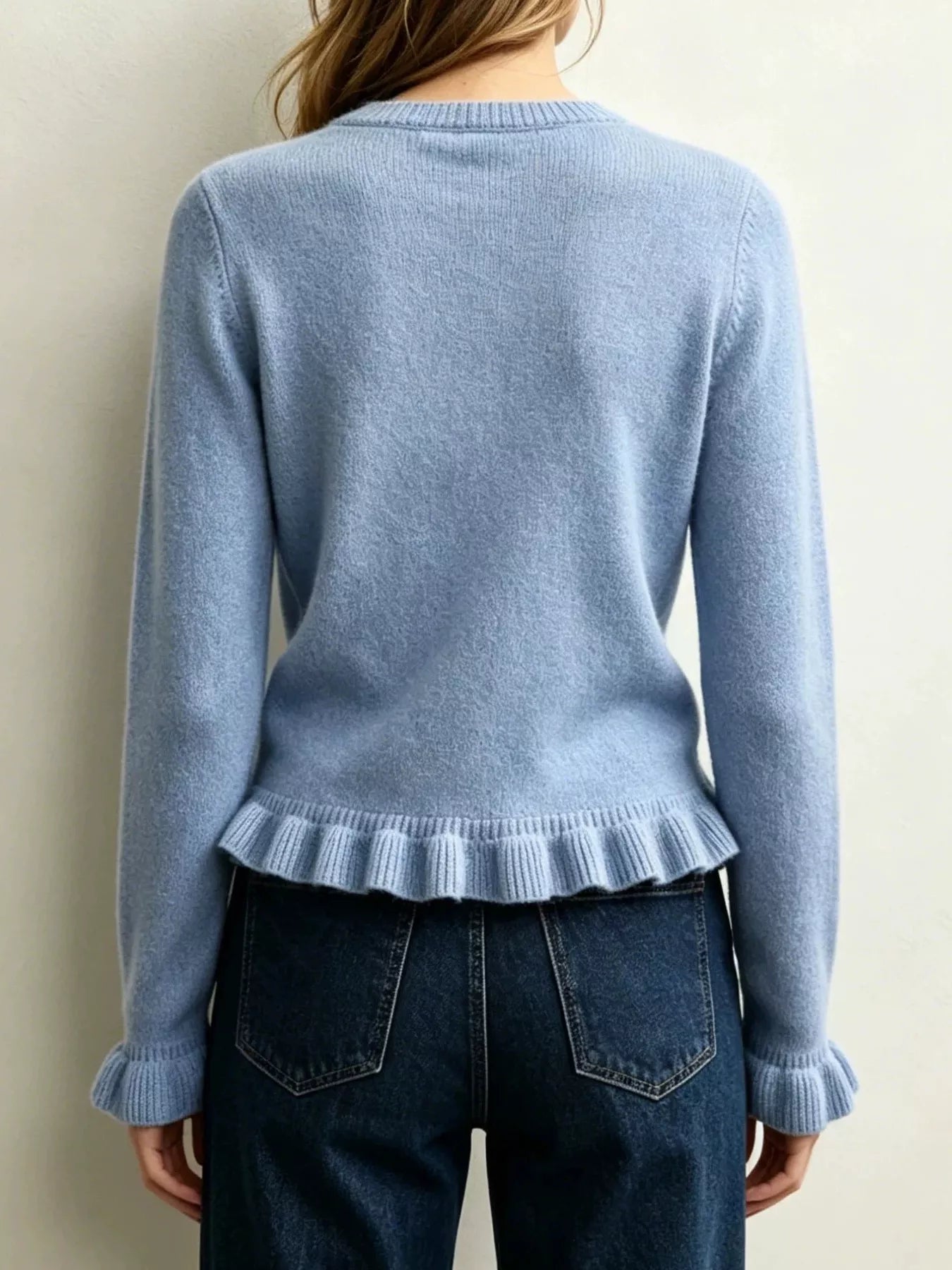 Back view on-model of light blue crew neck sweater with ruffled hem and cuffs