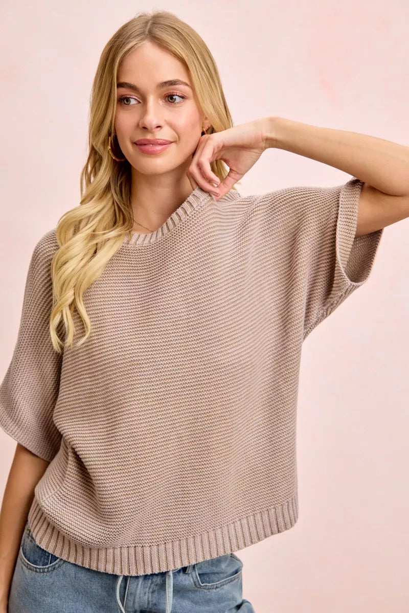 Front view of washed mocha dolman knit top with hand raised to neckline.
