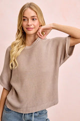 Front view of washed mocha dolman knit top with hand raised to neckline.