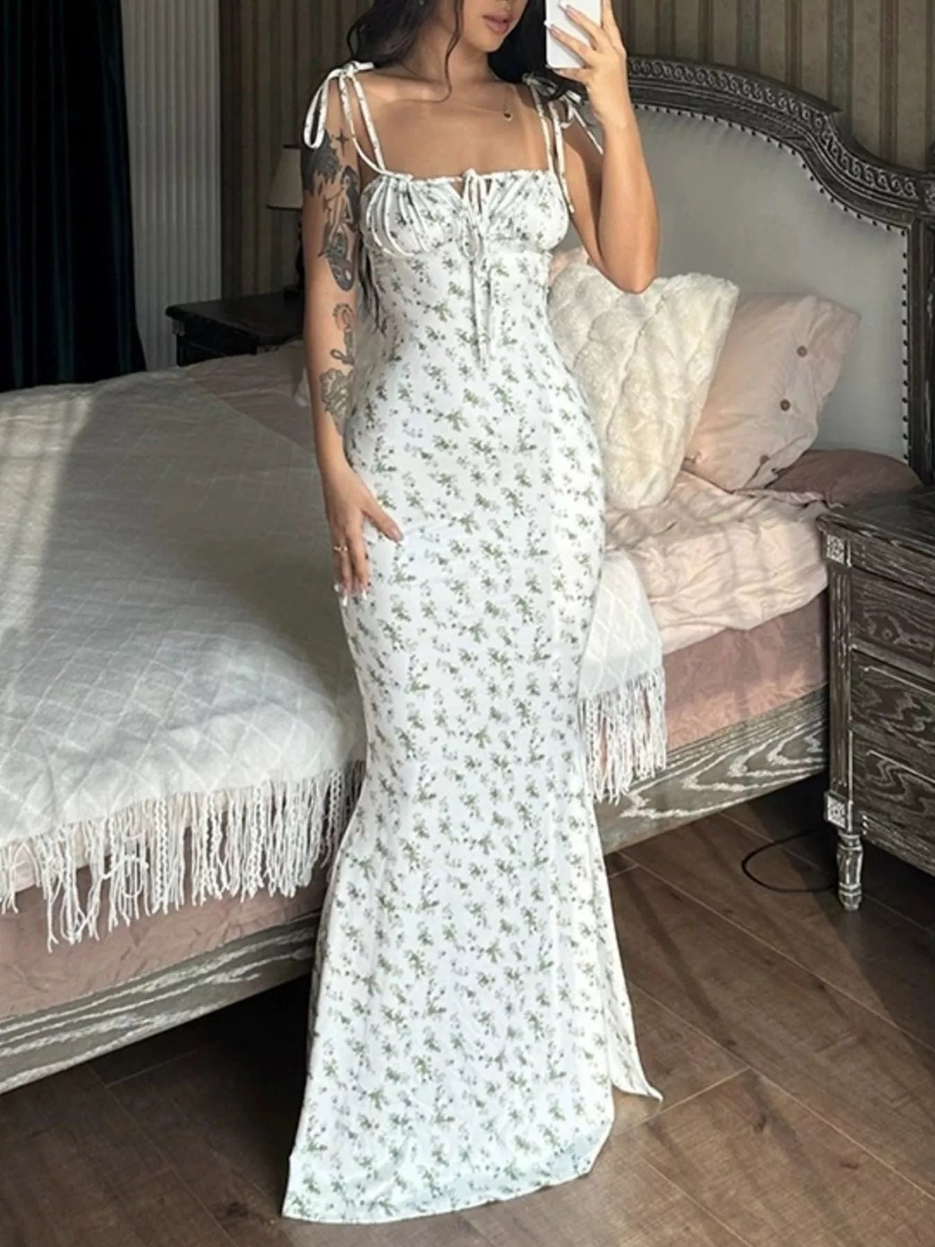 Model in mirror selfie wearing white floral print bodycon maxi dress with ruched bodice and tie straps