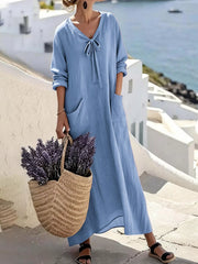 Model wearing sky blue long sleeve loose maxi dress outdoors, full view with large pockets and tie neck