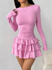 Pink layered ruffle mini dress worn front facing with one hand resting on the shoulder