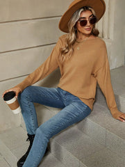 Seated front view of the camel dropped shoulder knit sweater with a ribbed neckline