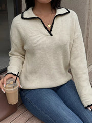 Seated front view of a cream dropped shoulder sweater with black scalloped collar trim