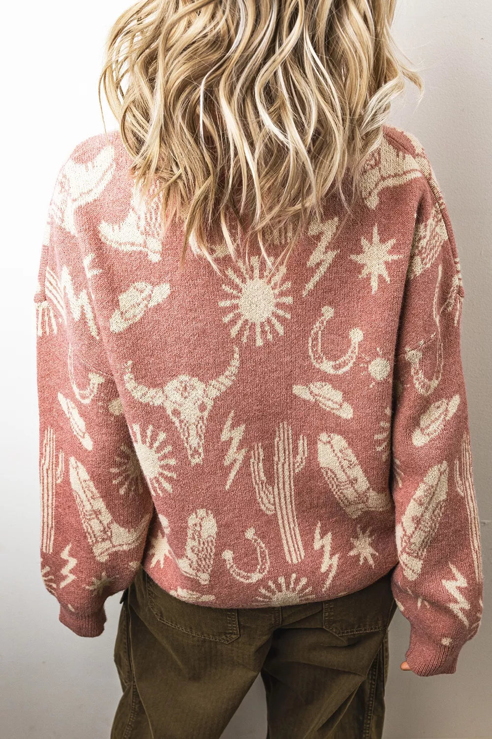 On-model back view of the dusty rose western sweater with cream cactus and sun motifs