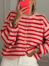 Mirror selfie close up of pink and red striped button down cardigan with white pants