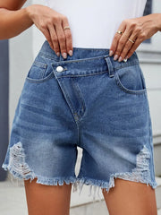 Women's distressed denim shorts with an asymmetrical waist, washed detailing, and raw hems.