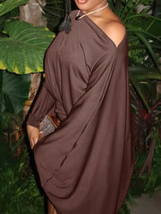 Side view of brown one shoulder draped bodycon mini dress outdoors among foliage