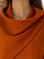 Close-up of the burnt orange cowl neckline showing the draped asymmetric collar and fine knit texture