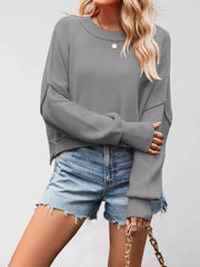 Front view of a gray crew neck dropped shoulder sweater with ribbed cuffs worn with denim shorts.