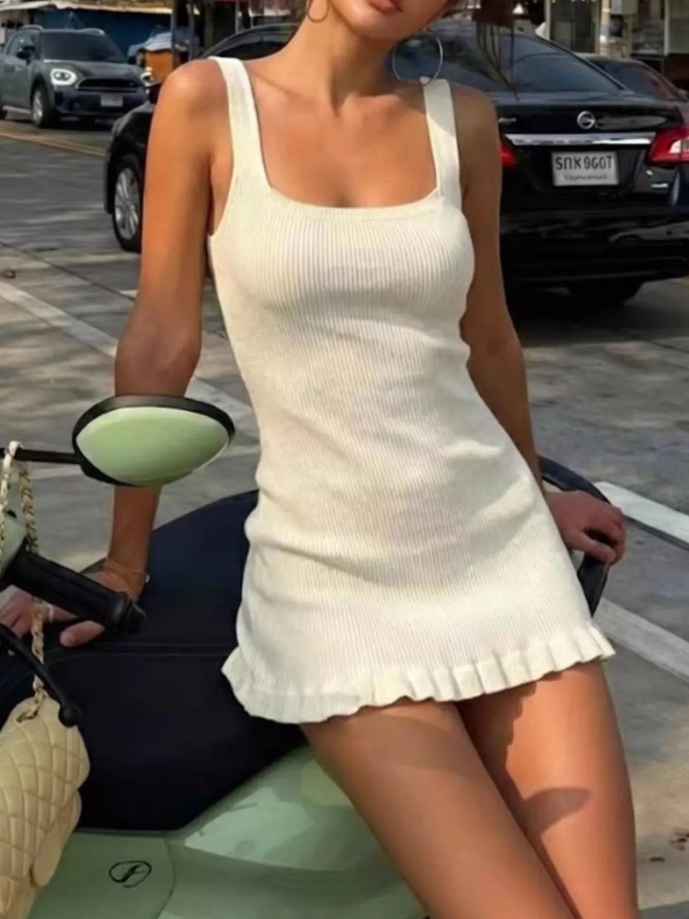 Front view of a cream ribbed knit square neck dress, seated outdoors.