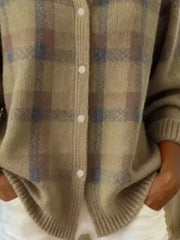 Close-up of the lower front and ribbed hem of a khaki plaid knit cardigan with white buttons