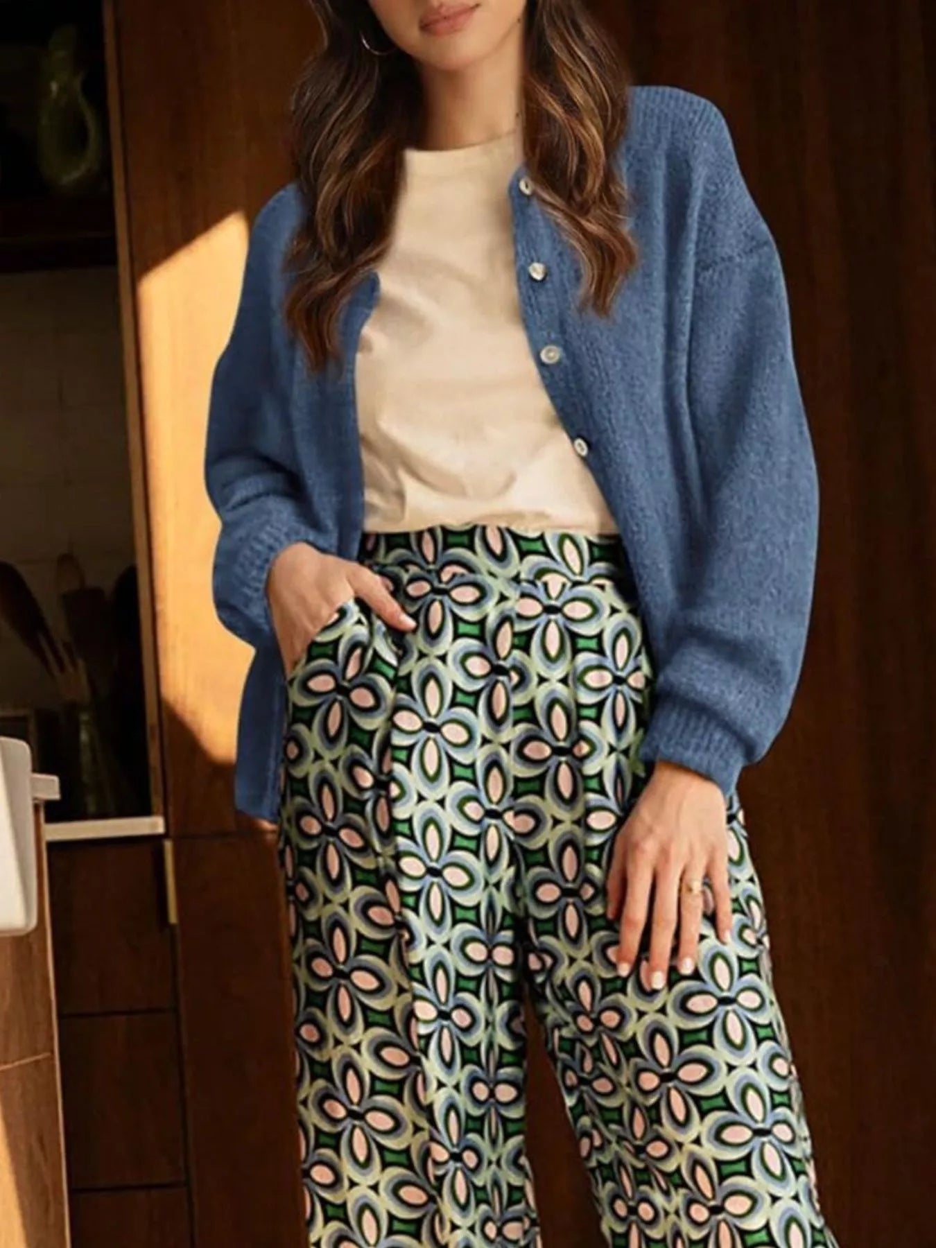 Full length view of open haze blue button down cardigan over a cream top and patterned trousers