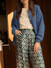 Full length view of open haze blue button down cardigan over a cream top and patterned trousers