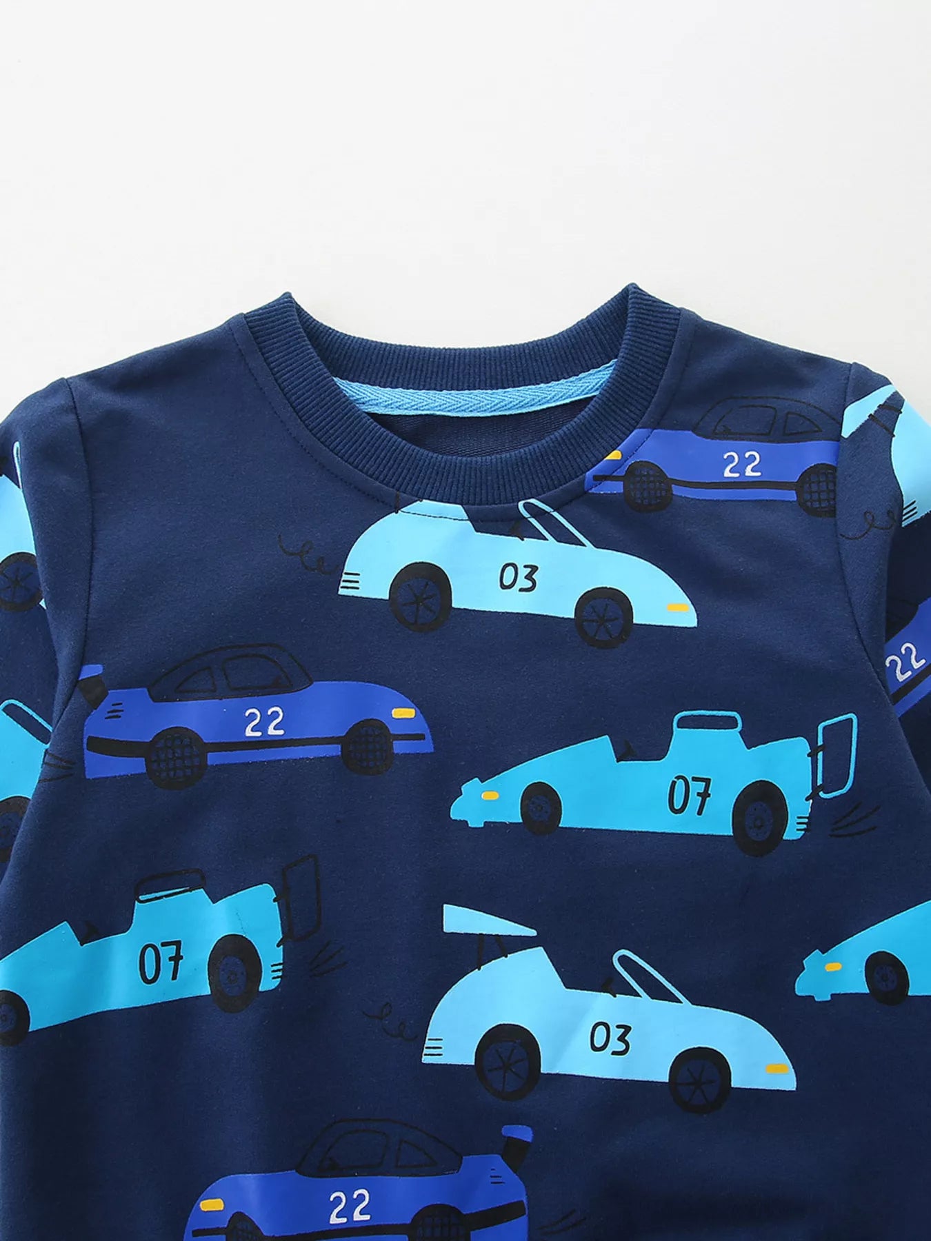 Close-up of the navy sweatshirt neckline with light blue trim and racing car print